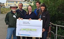 A group of people holding a blue print for the project