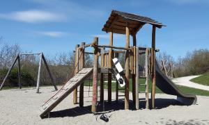 a wooden park playground with climbing apparatuses and swings