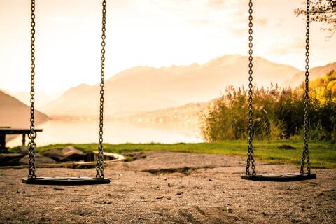 two swings in front of a mountain lake